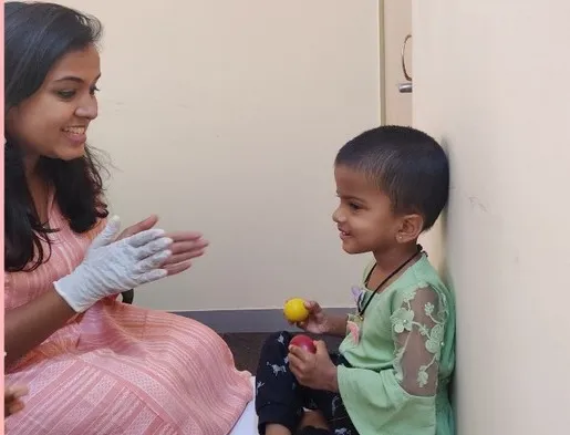 A therapist and a young boy playing with a musical toy
